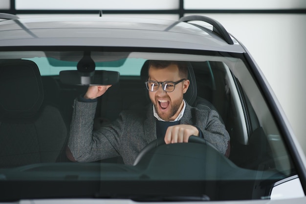 Visite d'un concessionnaire automobile Un bel homme barbu caresse sa nouvelle voiture et sourit