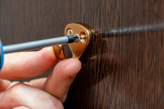 Visser la patère au mur de l'armoire avec un tournevis