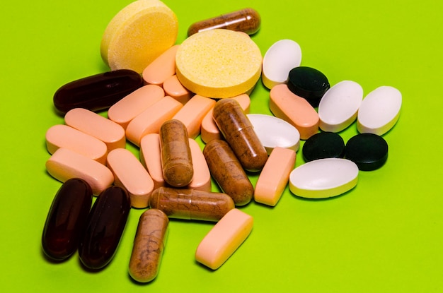 Vitamines en capsules et comprimés sur fond vert.