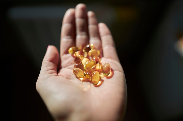 Vitamines dans l'huile de poisson oméga 3 de la main de la jeune fille en capsules vitamines pour l'immunité