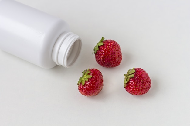 Vitamines fraîches sous forme de fraises de flacon de pilules blanches médecine.