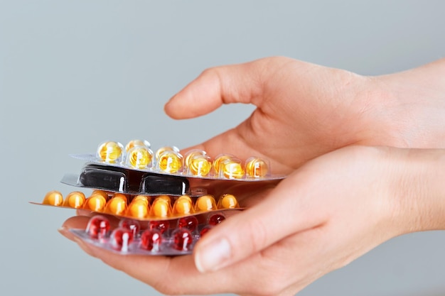 Vitamines et suppléments Gros plan de mains de femme tenant une variété de pilules de vitamines colorées
