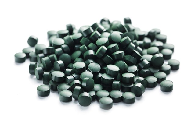 Les vitamines végétariennes de la spiruline sont dispersées sur un fond blanc avec de l'espace libre