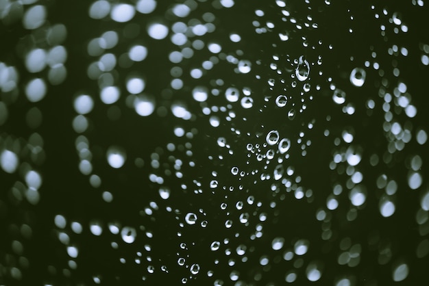 Vitre sale avec des gouttes de pluie. Fond vert atmosphérique