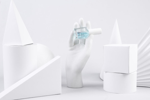 Vitrine de minimalisme créatif La main tient une bouteille de formes géométriques de vernis à ongles sur fond blanc Concept art Beauté et mode