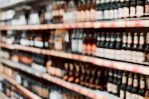 Des vitrines floues avec des produits alcoolisés bouteilles de vin et de bière debout sur des étagères en magasin