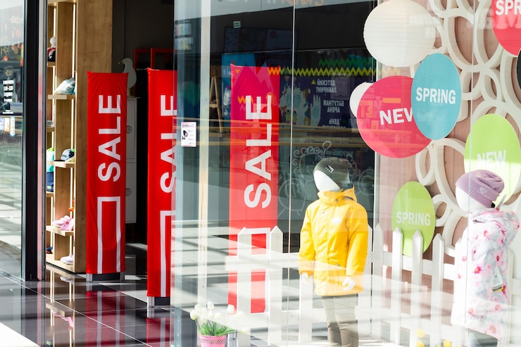 Vitrines d'un magasin de vêtements avec des stands rouges avec des panneaux de vente. Le temps des remises.