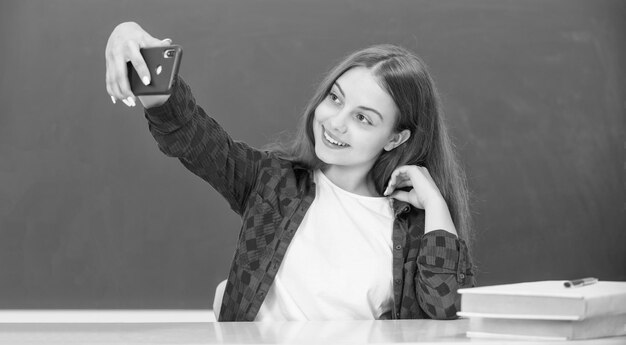 Vlogger blogueur scolaire avec téléphone portable en classe faisant un blog vidéo sur smartphone