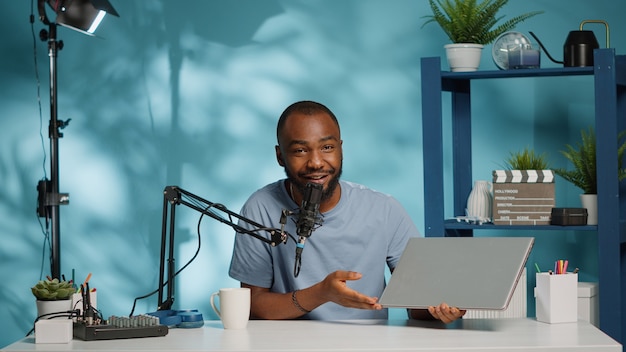 Vlogger examinant un ordinateur portable moderne pour les abonnés de la chaîne en studio. Influenceur effectuant une revue de produit de l'appareil pour vlog sur les réseaux sociaux. Blogger utilisant un gadget pour la recommandation de vidéos