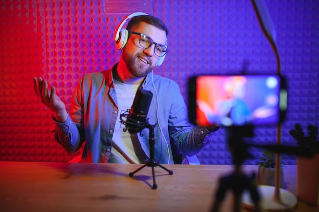 Vlogger utilisant un smartphone pour filmer un podcast en studio blogueur avec un microphone de téléphone portable et un casque filmant une vidéo pour une carrière de diffusion sur les réseaux sociaux