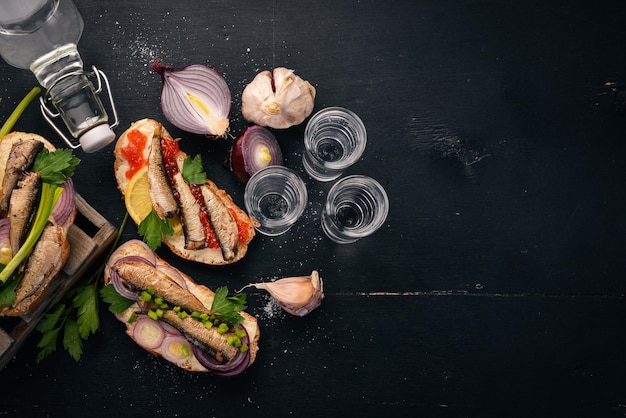 Vodka et un ensemble de sandwichs aux sprats et caviar oignon et persil sur un fond en bois Vue de dessus Espace de copie