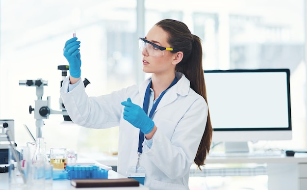 Le voici Photo recadrée d'une jeune scientifique concentrée mélangeant des produits chimiques à l'intérieur d'un laboratoire pendant la journée