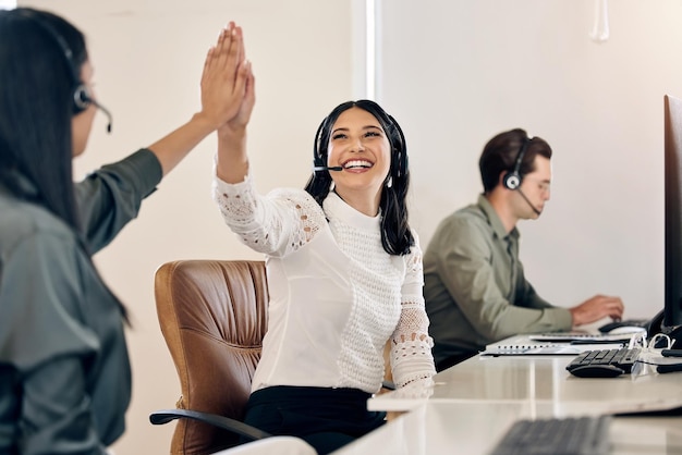 Voici pour faire toutes les grosses ventes aujourd'hui Photo d'un jeune agent de centre d'appels donnant à son collègue un high five dans un bureau