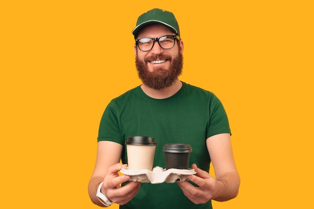 Voici votre café dit un sympathique barista ou livreur en uniforme vert