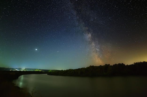 La Voie lactée et la planète Jupiter dans le ciel étoilé de la nuit au-dessus de la rivière. Un endroit merveilleux pour observer la nature.