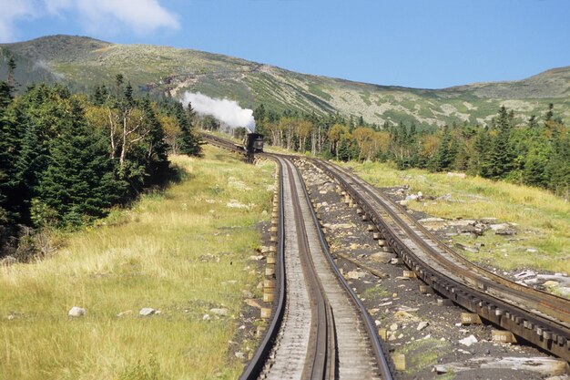 La voie de roue dentée du chemin de fer de Mount Washington par une journée ensoleillée avec une locomotive à vapeur en arrière-plan