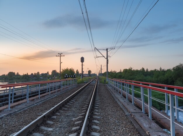 Voies ferrées sur le pont par la campagne dans la soirée