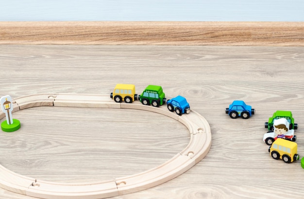 Voies de train jouet en bois écologique pour les tout-petits avec des voitures disposées de manière chaotique sur un sol stratifié.activités pour