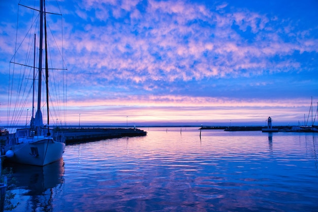 Voilier dans le port du lac Vaettern au coucher du soleil Phare en arrière-plan