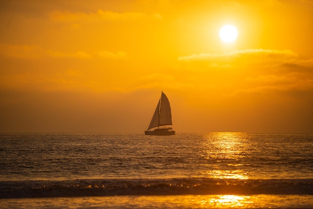 Voilier en mer coucher de soleil au lever du soleil sur la plage océan coloré nature paysage fond avec c...