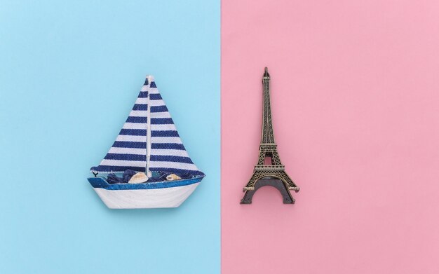 Voilier et Tour Eiffel sur fond rose bleu. Concept de voyage minimalisme. Vue de dessus. Mise à plat