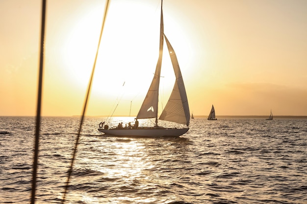 Voilier avec voiles blanches ouvertes en mer au coucher du soleil du soir fond d'horizon Aventure estivale de luxe sur yacht à voile