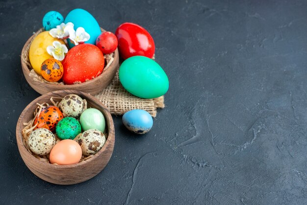 voir au-dessus des œufs de pâques colorés à l'intérieur des assiettes sur une surface sombre