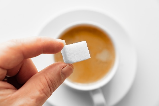 Voir en haut. tasse de café avec du lait et un cube de sucre à la main. petit déjeuner traditionnel du matin. vivacité dans les ascensions matinales. cappuccino