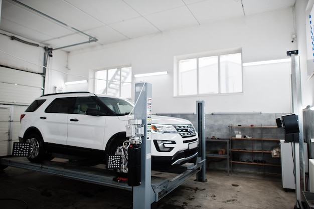 Photo voiture américaine suv sur support pour contrôle de carrossage d'alignement des roues dans l'atelier de la station-service