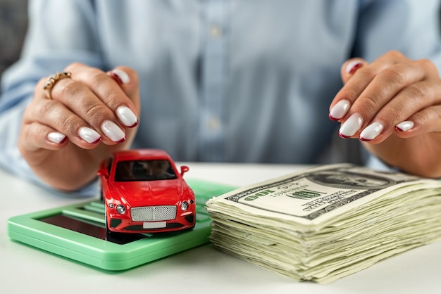 Voiture sur billets d'un dollar américain et calculatrice sur table en verre avec les mains sur la voiture