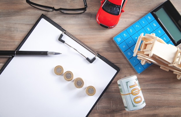 Voiture, billets en dollars, calculatrice sur le bureau.