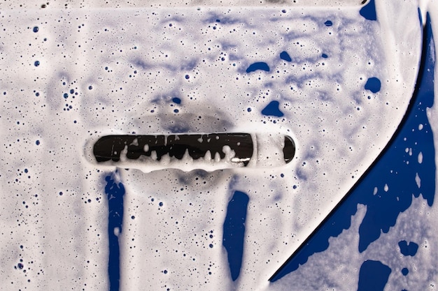 Photo voiture bleue en mousse dans un lave-auto