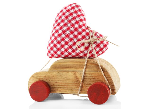 Voiture en bois avec un coeur en tissu rouge attaché à elle isolé sur blanc