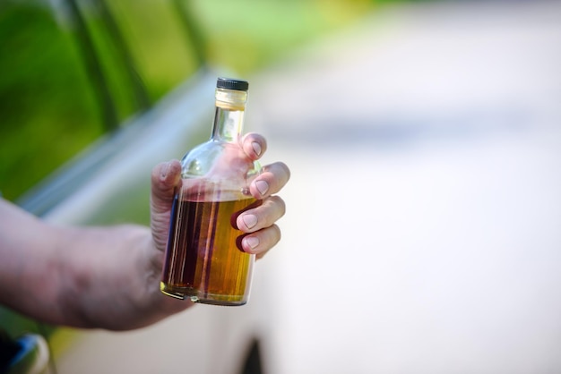 Voiture de bouteille d'alcool et concept de conduite en état d'ébriété la personne tient en main une bouteille de boisson alcoolisée au volant de la voiture
