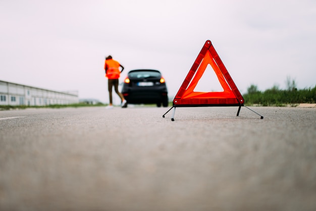 Voiture cassée sur la route. Triangle d&#39;avertissement rouge.