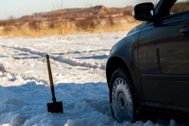 Voiture coincée dans la neige tout-terrain à la lumière du jour avec pelle et mise au point sélective