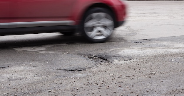 La Voiture Contourne Un Nid De Poule Sur La Route. Asphalte Cassé Après L'hiver.