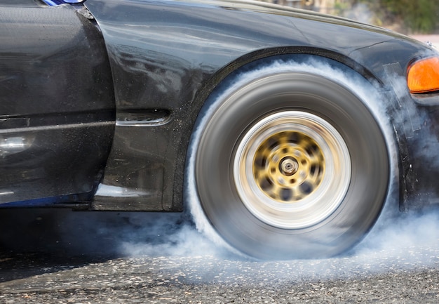 La voiture de course de drag brûle le caoutchouc de ses pneus en préparation pour la course