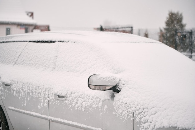 Une voiture couverte de neige dans la tempête hivernale