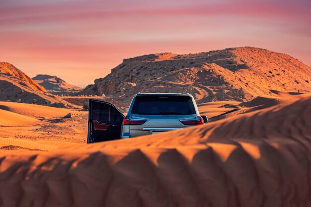 Photo voiture dans le désert contre le ciel au coucher du soleil