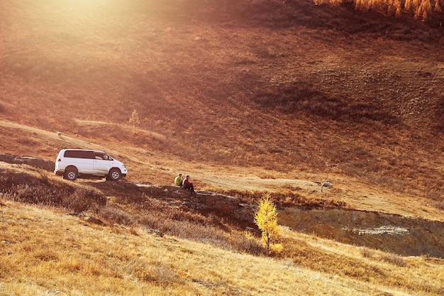 Voiture et deux personnes au coucher du soleil dans les montagnes de l'Altaï en Russie