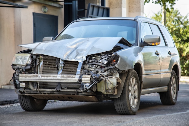 Voiture écrasée dans un accident de voiture. Véhicule cassé après une catastrophe fatale. Dommages causés par les collisions routières. La voiture grise est endommagée par accident. Automobile endommagée après collision.