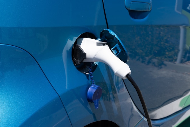 Voiture électrique, charger l'énergie de la batterie dans le véhicule bleu de la station