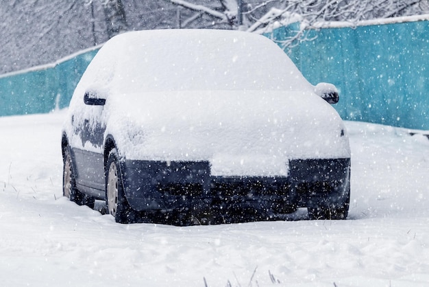 Une voiture enneigée sur le bord de la route lors d'une chute de neige