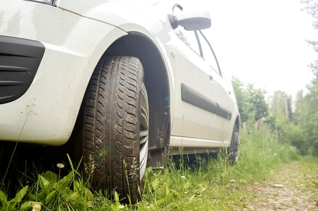 La voiture est venue dans la forêt et se tient sur l'herbe près du chemin de terre parmi les arbres