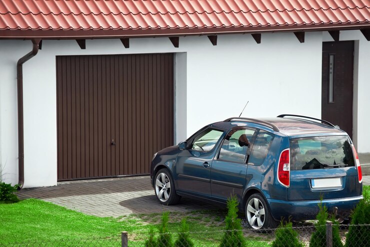 Photo voiture familiale bleue garée près du garage de la maison individuelle