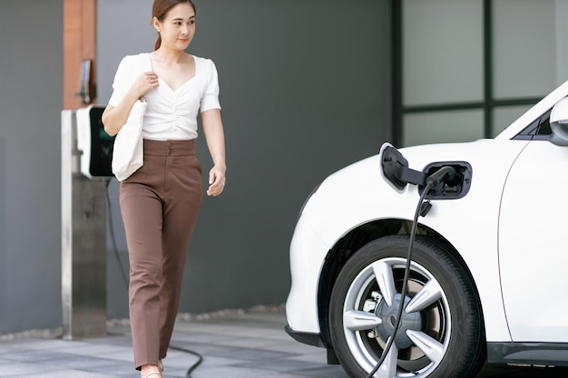 Voiture Focus EV à la station de charge à domicile avec une femme floue progressive à l'arrière