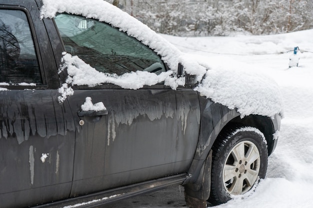 Voiture gelée couverte de neige un jour d'hiver pare-brise et capot dans la neige