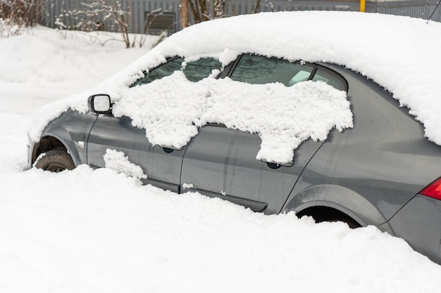 Voiture gelée couverte de neige un jour d'hiver pare-brise et capot dans la neige