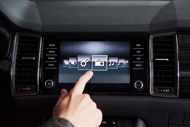 Photo voiture intelligente et internet des objets iot concept. le doigt pointe vers la console de la voiture et les icônes surgissent de l'écran
